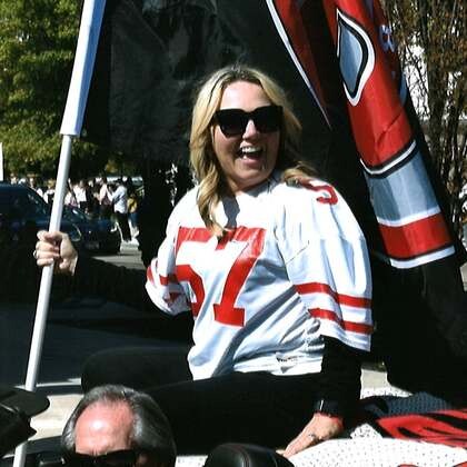 Principal Deb Watts riding in a convertible and holding a Boise High flag